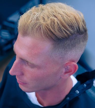 Man with short, textured blonde hair and a faded haircut, looking to the side.