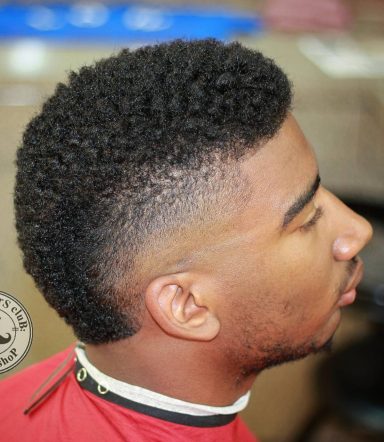 Close-up of a man with a curly haircut and a faded side profile.